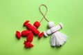 Traditional martisor shaped as man and woman on green background, top view. Beginning of spring celebration