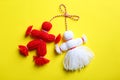Traditional martisor shaped as man and woman on yellow background, top view. Beginning of spring celebration