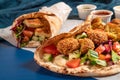 Traditional Mediterranean Arabic grilled halloumi and falafel, hummus and vegetables in flatbread wraps with herbs and sauces