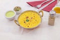 Traditional metal serving bowl in Indian and Pakistani restaurants with a chicken korma recipe with vegetable chunks and green