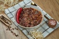 A traditional Mexican dish is chili con carne soup with stewed beef in a composition with spices on a wooden background. Tasty