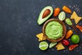 Traditional mexican food. Bowl guacamole sauce with avocado, lime and nachos on black table top view. Copy space for recipe. Royalty Free Stock Photo