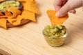 Traditional Mexican food. woman using hand eating nachos dip with guacamole sauce consist of avocado, tomato and cilantro. Royalty Free Stock Photo