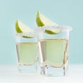 Traditional mexican golden tequila alcohol drink with lime and salt edge in shot glass on elegant blue color background, square. Royalty Free Stock Photo