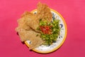 Mexican guacamole with pork chicharron on pink background