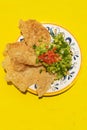 Mexican guacamole with pork chicharron on yellow background