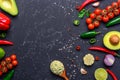 Traditional Mexican Guacamole sauce in spoon and ingredients on black stone table. Top view with copy space Royalty Free Stock Photo