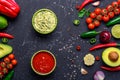 Traditional Mexican Latin American Salsa sauce and Guacamole and ingredients on black stone table. Top view Royalty Free Stock Photo