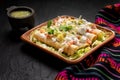 Mexican potato and cheese fried tacos also called flautas with green sauce on dark background