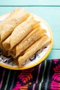 Mexican potato and cheese fried tacos also called flautas on turquoise background