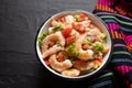 Mexican shrimp ceviche with tomato and serrano pepper on black background