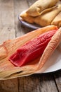 Mexican sweet tamales with strawberry jam on wooden background