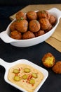 Traditional Middle Eastern food, Falafel (tamiya) with hummus and pickles on black wooden background and yellow table cloth.