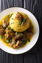 Traditional Mofongo with plantains, garlic and chicharron served with meat and broth close-up on a plate. Vertical top view