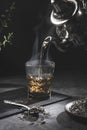 Traditional Moroccan teapot pouring tea into a steaming glass with natural tea and mint, on a dark background. Traditional Royalty Free Stock Photo