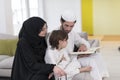 Traditional muslim family parents with children reading Quran and praying together on the sofa before iftar dinner Royalty Free Stock Photo