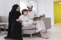 Traditional muslim family parents with children reading Quran and praying together on the sofa before iftar dinner Royalty Free Stock Photo