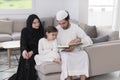 Traditional muslim family parents with children reading Quran and praying together on the sofa before iftar dinner Royalty Free Stock Photo