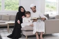 Traditional muslim family parents with children reading Quran and praying together on the sofa before iftar dinner Royalty Free Stock Photo