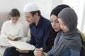 Traditional muslim family parents with children reading Quran and praying together on the sofa before iftar dinner Royalty Free Stock Photo