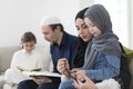 Traditional muslim family parents with children reading Quran and praying together on the sofa before iftar dinner Royalty Free Stock Photo