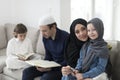 Traditional muslim family parents with children reading Quran and praying together on the sofa before iftar dinner Royalty Free Stock Photo