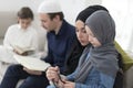 Traditional muslim family parents with children reading Quran and praying together on the sofa before iftar dinner Royalty Free Stock Photo