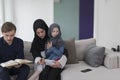 Traditional muslim family parents with children reading Quran and praying together on the sofa before iftar dinner Royalty Free Stock Photo