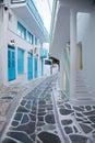 traditional narrow street in Mykonos with blue doors and white walls