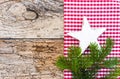 Natural Christmas decoration with white star shape and green fir branch on old wood background and red checkered fabric Royalty Free Stock Photo