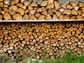 A traditional neat pile of chopped firewood in different shapes with grass in Switzerland