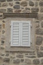 Traditional new white window shutters as blinds on old stone home Royalty Free Stock Photo