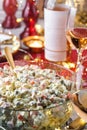 Traditional New Year salad Olivier in bowl on wooden table served with plates, glasses, bottle of wine, candles, garland, festive Royalty Free Stock Photo