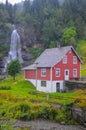 Traditional norwegian red wooden house and Steinsdalsfossen waterfall in the background, Norway Royalty Free Stock Photo