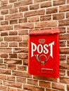 Traditional red postbox fixed on house brick wall by house entrance used for mail & letter delivery. Royalty Free Stock Photo