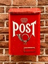 Traditional red postbox fixed on house brick wall by house entrance used for mail & letter delivery. Royalty Free Stock Photo