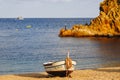 Traditional old wooden fishing boat on the rocky beach. Travel concept. Costa Brava, Spain. Fishing boat rest on golden sand beach Royalty Free Stock Photo