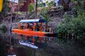 Traditional orange trajinera in Xochimilco lake with trees as background