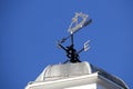 Traditional ornate weather vane or weathercock in a a ship design on top of an old building against blue sky Royalty Free Stock Photo