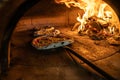 Traditional oven for baking pizza with burning wood and shovel. The cook rotates the pizza in the oven to ensure even baking Royalty Free Stock Photo