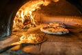 Traditional oven for baking pizza with burning wood and shovel. The cook rotates the pizza in the oven to ensure even baking Royalty Free Stock Photo