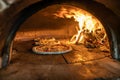 Traditional oven for baking pizza with burning wood and shovel. Several pizzas are baked in a brick oven Royalty Free Stock Photo