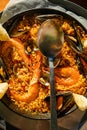 Traditional Paella served at restaurant seafood paella in the fry pan with a huge iron spoon, shrimp and mussels, lemon