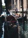 Traditional parked gondola with blurred tourists and gondolier on the background