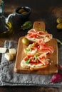 Traditional parma cured ham antipasto. Bruschetta set with Parma Ham and Parmesan Cheese. Small sandwiches with prosciutto,