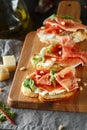 Traditional parma cured ham antipasto. Bruschetta set with Parma Ham and Parmesan Cheese. Small sandwiches with prosciutto,