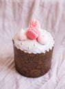 A traditional paska decorated with pink swiss chocolate and meringue stands on a pink tablecloth. Easter holiday, top view. Place