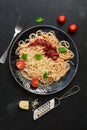 Traditional pasta spaghetti with tomato sauce, parmesan cheese and greens on a black stone background. Top view, flat lay Royalty Free Stock Photo