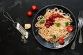 Traditional pasta spaghetti with tomato sauce, parmesan cheese and greens on a black stone background. Overhead view, flat lay Royalty Free Stock Photo