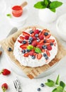 Traditional Pavlova cake with fresh strawberries, blueberries, raspberries, whipped cream and strawberry sauce. Royalty Free Stock Photo